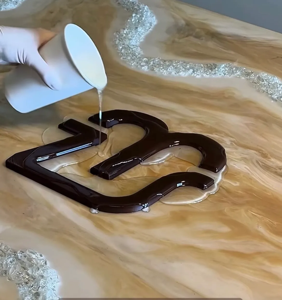 Epoxigyanta öntése egy 3D nyomtatott, barna PETG logóelemre öntőteszt közben